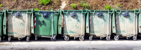 Trash or garbage cans standing in a row outdoors.の写真素材