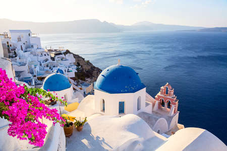 Famous Santorini iconic view. Blue domes and traditional white houses with bougainvillea flowers. Oia village, Santorini island, Greeceの写真素材