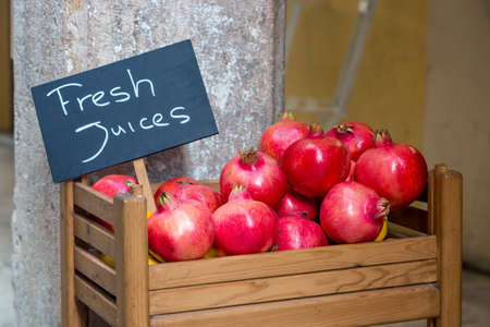 Fresh ripe red pomegranates in wooden box with inscription fresh juices.の写真素材