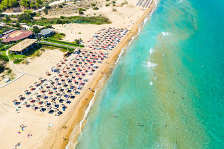 Top view aerial drone photo of Banana beach with beautiful turquoise water, sea waves and red umbrellas. Vacation travel background. Ionian sea, Zakynthos Island, Greece.の写真素材