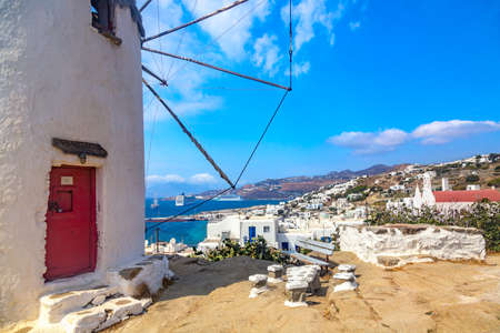 Famous old windmill in Chora with city view. Summer sunny day. Mykonos island, Greece.