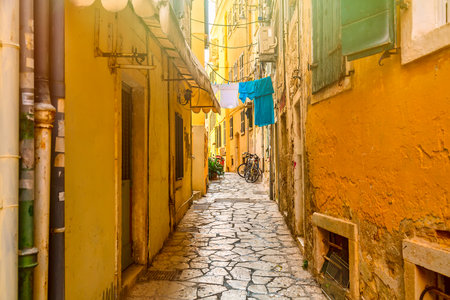 Kerkyra city narrow street view with yellow colorful houses and bikes during sunny day. Corfu Island, Ionian Sea, Greeceのeditorial素材