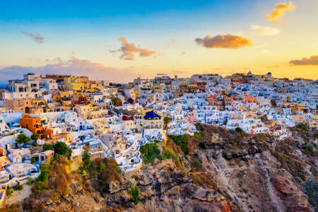 Aerial drone view of famous Oia village with white houses and blue dome churches during sunrise on Santorini island, Aegean sea, Greeceの写真素材