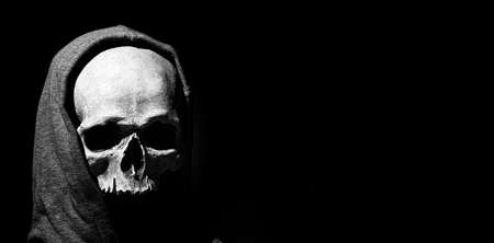 Human skull in hood close up on black background. Free space.の写真素材