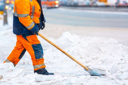 Communal services worker removes snow from road in winter, Cleaning city streets and roads during snowstorm. Moscow, Russiaの写真素材