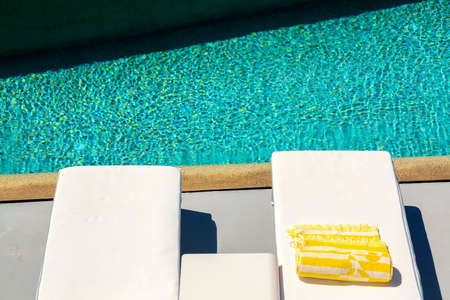 Luxury resort on Santorini, Greece. Sunbeds with towel near swimming pool. Vacation and relaxation backgroundの写真素材