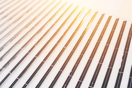 Renewable energy concept. Aerial drone view of solar panels power plant with sunlight in winter.