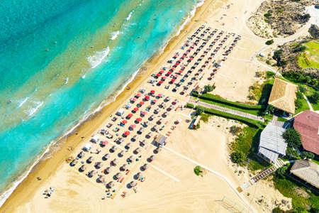 Top view aerial drone photo of Banana beach with beautiful turquoise water, sea waves and red umbrellas. Vacation travel background. Ionian sea, Zakynthos Island, Greece.の写真素材