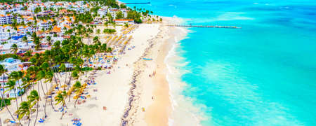 Beach vacation and travel background. Aerial drone view of beautiful atlantic tropical beach with straw umbrellas, palms and boats. Bavaro beach, Punta Cana, Dominican Republicの写真素材