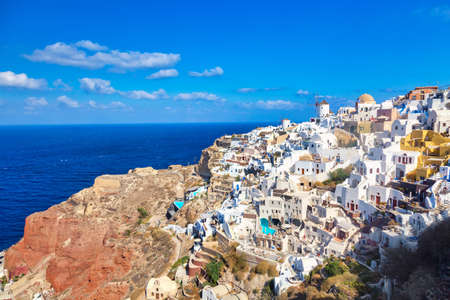 Greece holiday background. Famous iconic Oia village with traditional white houses and windmills during summer sunny day. Santorini island, Greeceの写真素材