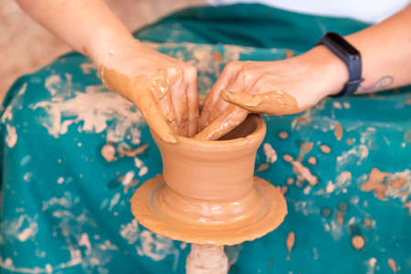 Female potter making ceramic pot on the pottery wheel.
