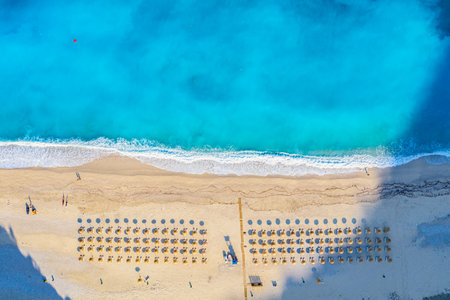 Top view aerial drone photo of Myrtos beach with beautiful turquoise water, sea waves and straw umbrellas. Vacation travel background. Ionian sea, Kefalonia Island, Greece.の写真素材