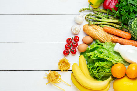 Food and grocery supermarket shopping. Vegetables, fruits assortment, eggs, pasta, champignons and bottle of milk on white wooden background. Vegetarian healthy food conceptの写真素材