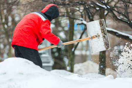 Communal services worker removes snow from road in winter. Cleaning city streets and roads after snow storm in Moscow, Russia.の写真素材