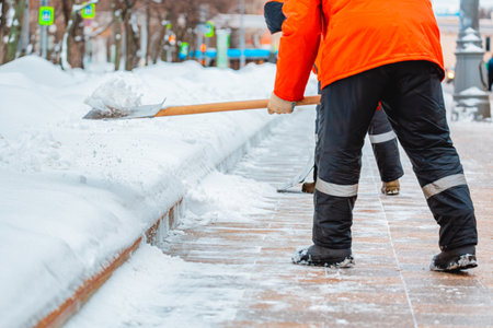 Communal services workers sweep snow from road in winter. Cleaning city streets and roads after snow storm in Moscow, Russiaの写真素材