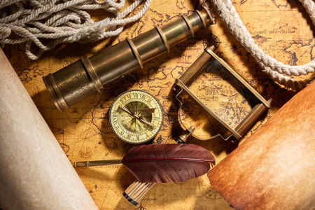 Travel geography background. Old spyglass, rope, vintage compass, quill, scrolls and magnifying glass on geographical vintage atlas map of the worldの写真素材