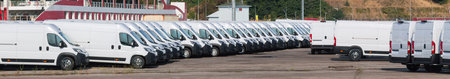 Commercial cargo transport and delivery concept. Many white cargo vans on the street. Small car trucks in a row. Banner wide format.の写真素材