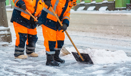 Communal services workers sweep snow from road in winter. Cleaning city streets and roads after snow storm in Moscow, Russiaの写真素材
