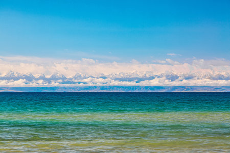 Panoramic view of Lake Issyk-Kul with clear water and blue sky with clouds in Kyrgyzstan. Nature landscape of Issyk-Kul in Kyrgyz Republic with Tien-Shan mountains.の写真素材