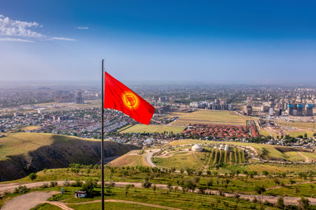 Aerial drone view of Bishkek city with the National flag of Kyrgyzstan on Mount Boz-Boltok during summer sunny day. Bishkek is the capital city of Kyrgyzstan.の写真素材