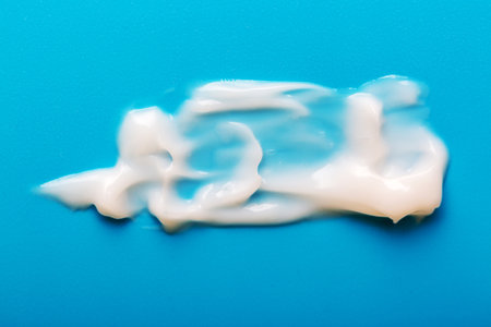 Cosmetic white cream smear on blue background. Beauty skincare creamy product. White lotion textureの写真素材