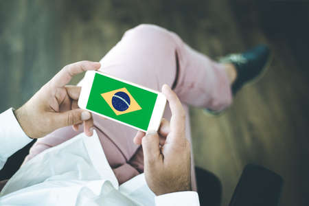 People using smart phone and showing on the screen the flag of BRAZILの写真素材