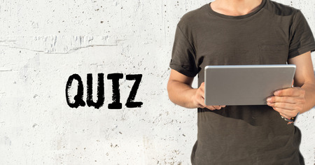 Young man using tablet pc and QUIZ concept on wall backgroundの写真素材