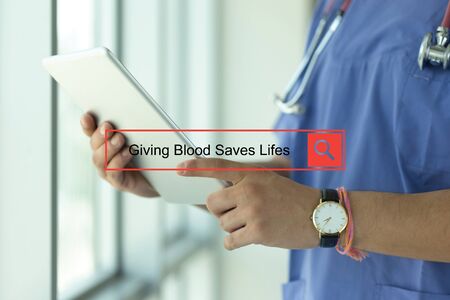 DOCTOR USING TABLET PC SEARCHING GIVING BLOOD SAVES LIFESの写真素材
