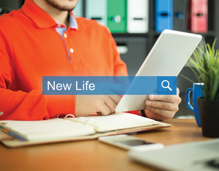 Young man working in an office with tablet pc and searching NEW LIFE word on internetの写真素材