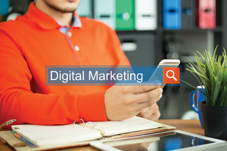Young man using smartphone and searching DIGITAL MARKETING word on internetの写真素材