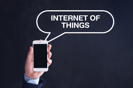 Hand Holding Smartphone with INTERNET OF THINGS written speech bubbleの写真素材