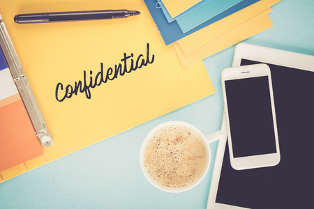 Notepad on workplace table and written CONFIDENTIAL conceptの写真素材