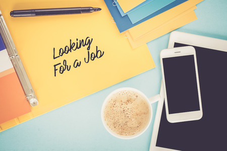 Notepad on workplace table and written LOOKING FOR A JOB conceptの写真素材