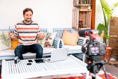 Expressive caucasian man smiling while records content for his vlog. Focus on man.の写真素材