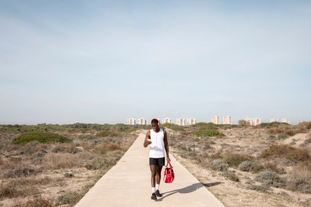 Young black athlete with headphones who comes to train while using his cell phone. Concept of sport.の写真素材