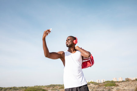 Young black sportsman with headset looking for coverage with his cell phone. Concept of technology.の写真素材