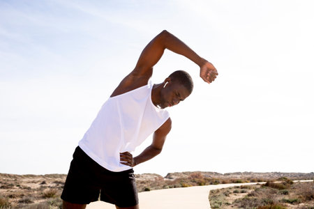 Middle shot of young black sports trainer doing stretching and warm-ups before training. Concept of health.の写真素材