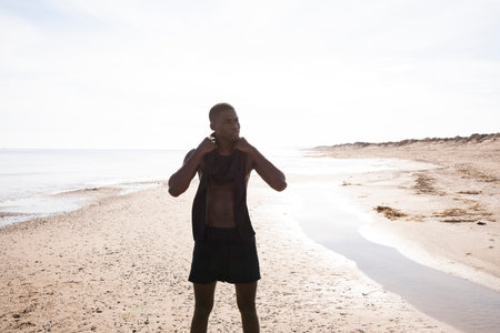 Healthy young athletic man wearing sport clothes at the beach with back light sun.の写真素材