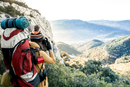 Girl hiker with backpack who photographs a mountain landscape. Travel Lifestyle concept adventure summer vacations outdoor.の写真素材