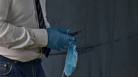 businessman with mobile phone and protective mask, concept of new objects of daily life due to the virusの写真素材
