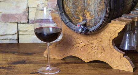 Glass of red wine with an old barrel in the background