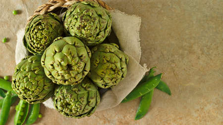 composition with raw artichokes with peas in a shower and wild plantsの写真素材