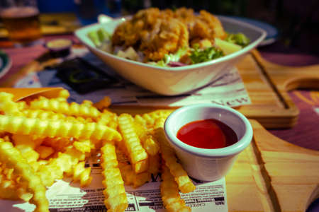 tomato sauce with a spicy touch and French fries, Caesar salad in the background.
