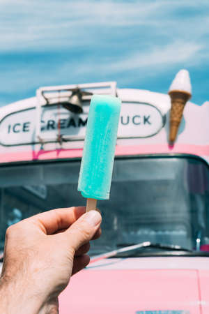Pastel blue ice cream with a pink ice cream truck or van in the background. Handの写真素材