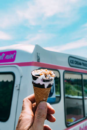 Ice cream cone with a pink ice cream truck or van in the background.
