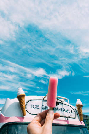 Pink ice cream with a pink ice cream truck or van in the background. Handの写真素材