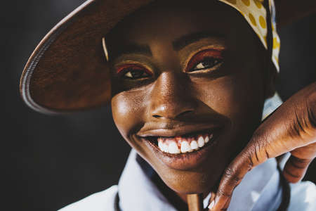 Black model with a pretty smile against a dark background.の写真素材