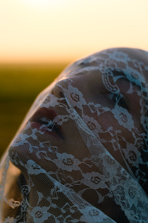 Close-up portrait of a veiled woman. White lace covering her face.の写真素材