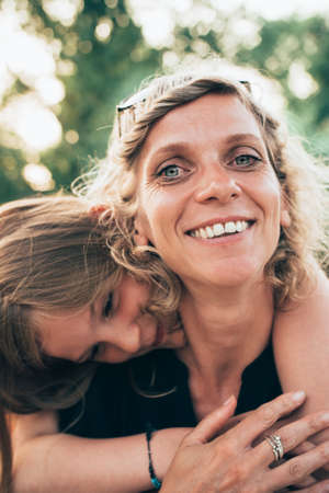 Mother and daughter togetherness in summer sun. Hugging each other.