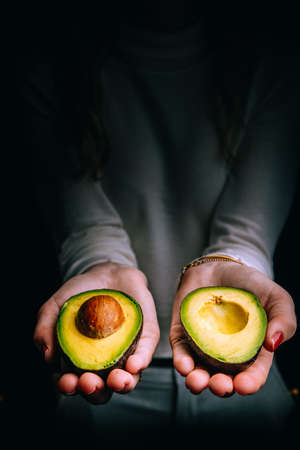 Sliced avocado in female hands.の写真素材